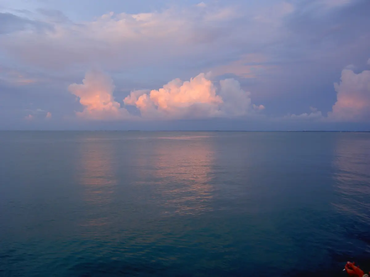 Evening clouds reflected in still water of the bay