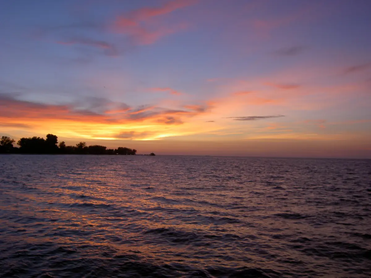 Pink and orange dusk sky over calm bay water