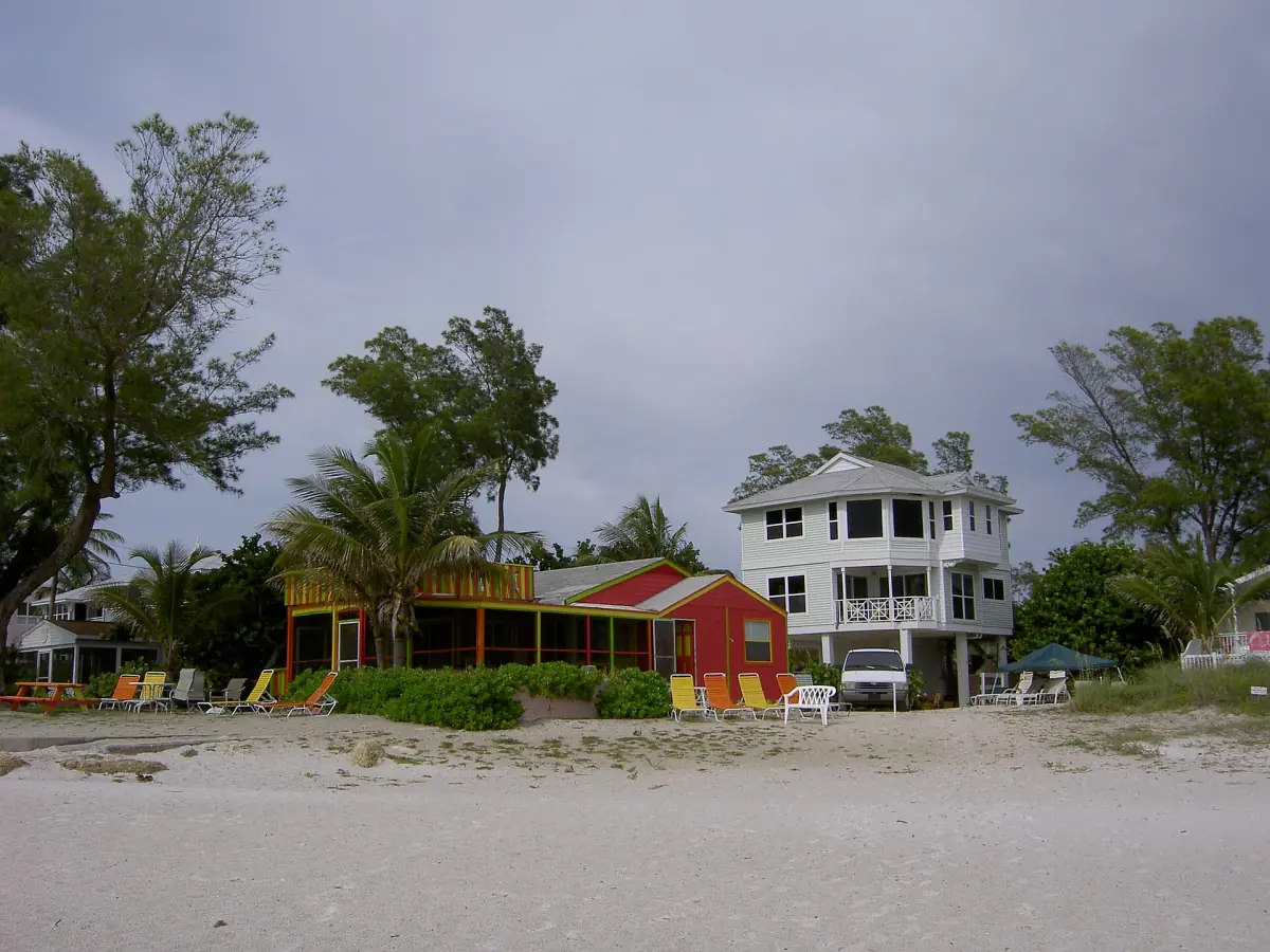 Colorful low cottage next to a large white house near the beach