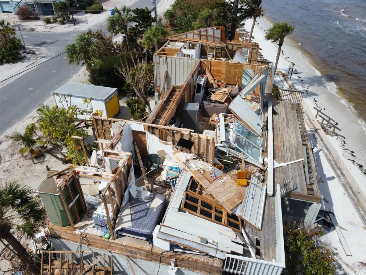 Aerial view of a collapsed wooden house on the beach side street