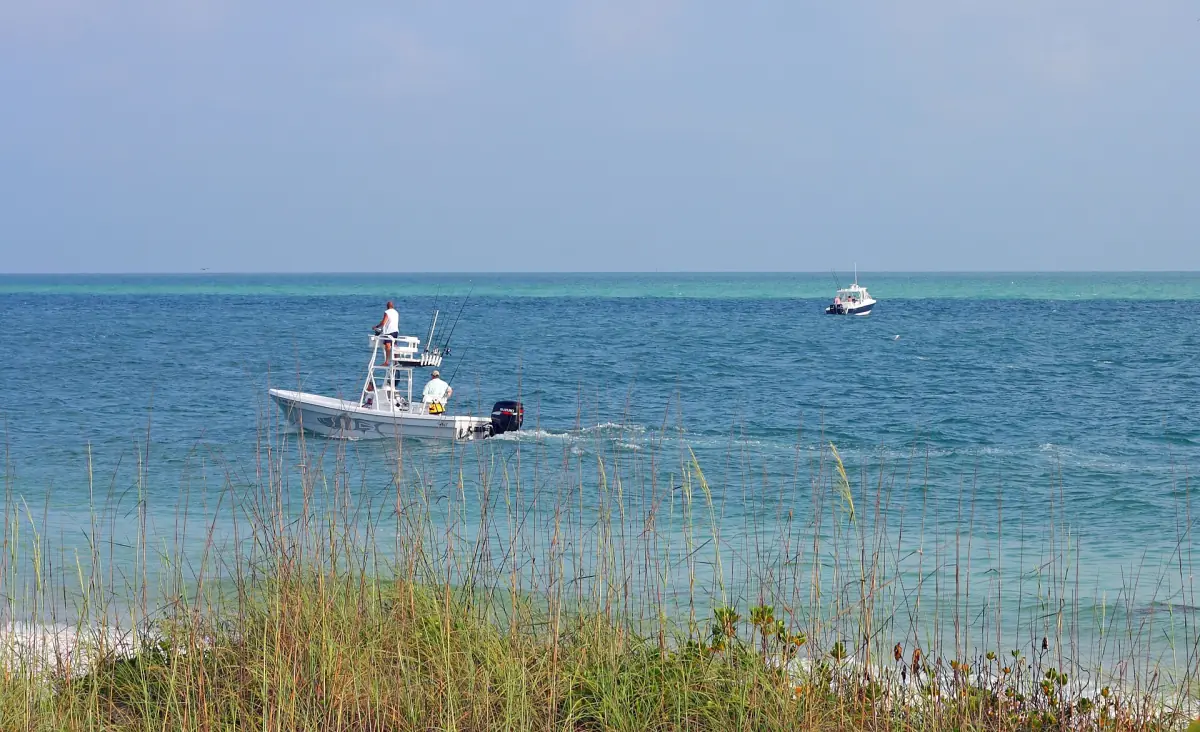 Small boat on the calm turquoise Gulf behind sea oats