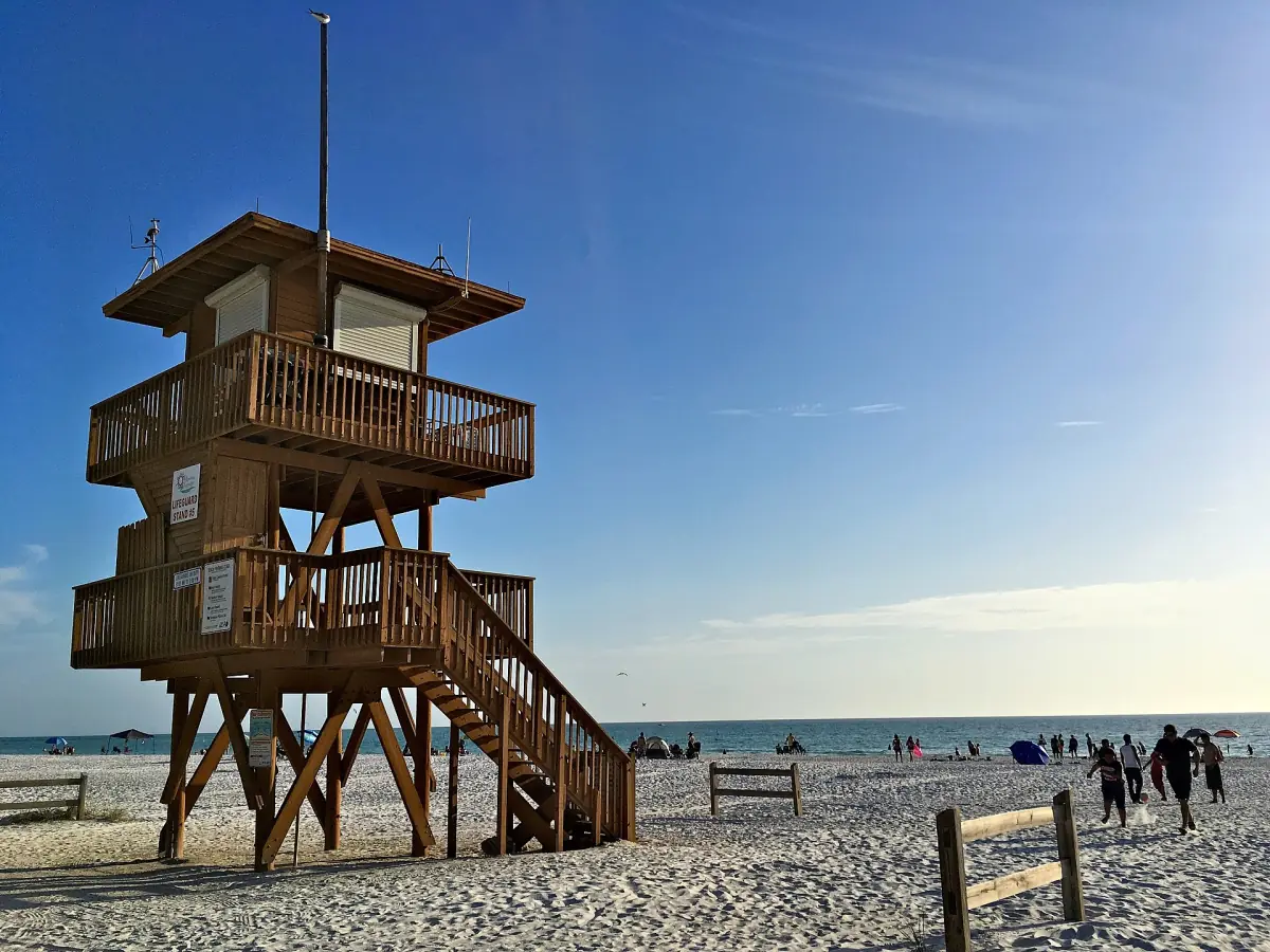 Wooden lifeguard tower on the beach with a few visitors in the distance