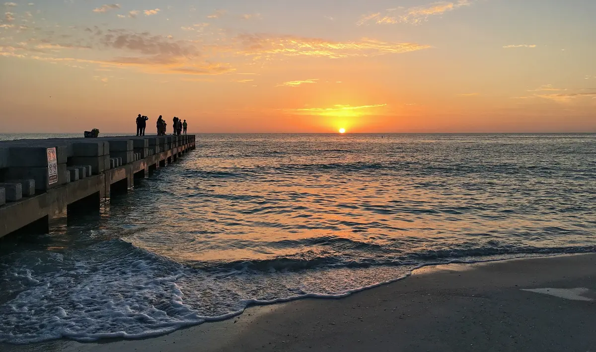 Concrete groyne reaching into the Gulf at sunset with gentle waves