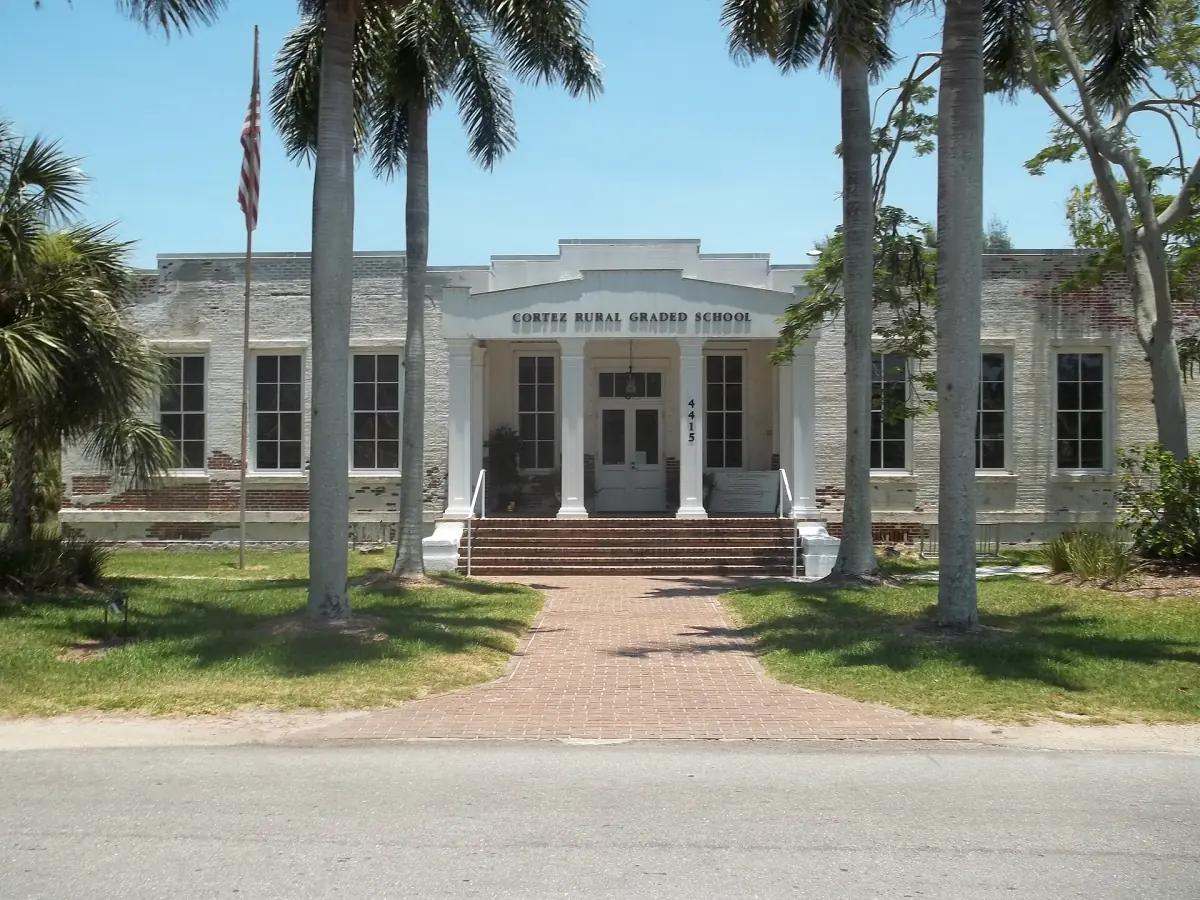 Historic school building with palms and a brick path in Cortez